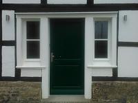Holz-Haustür in dunkelgrün mit weißen Fenstern beidseitig