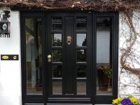 Holz-Haustür in schwarz mit Seitenteilen und Türklopfer