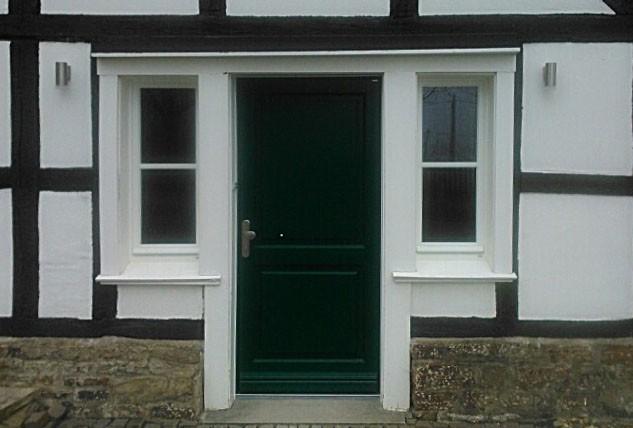 Holz-Haustür in dunkelgrün mit weißen Fenstern beidseitig